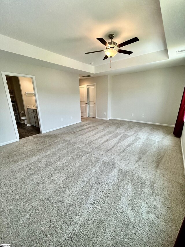 unfurnished bedroom with a raised ceiling, carpet, visible vents, and baseboards