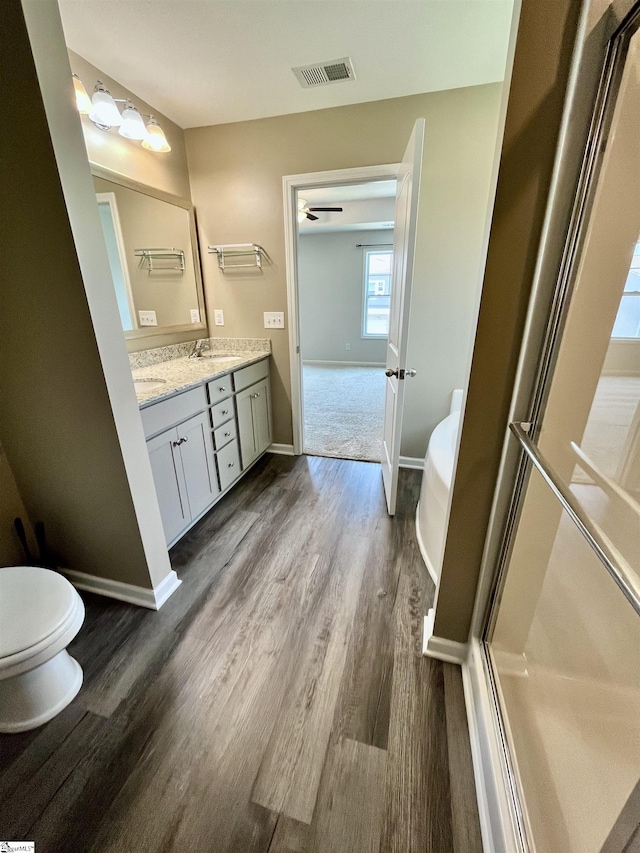 full bathroom with toilet, baseboards, visible vents, wood finished floors, and vanity