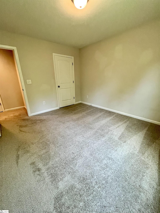 unfurnished room featuring baseboards and carpet