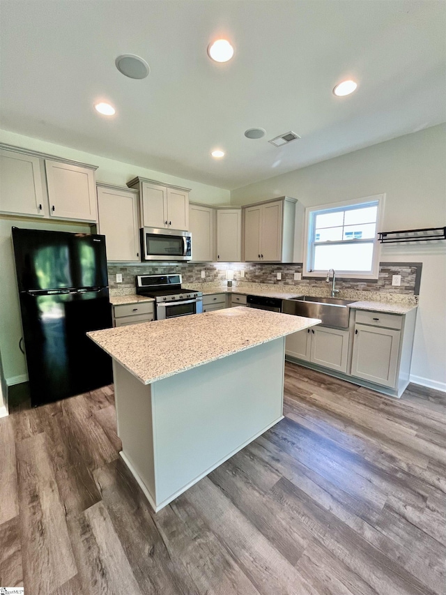kitchen featuring a sink, visible vents, backsplash, a kitchen island, and appliances with stainless steel finishes
