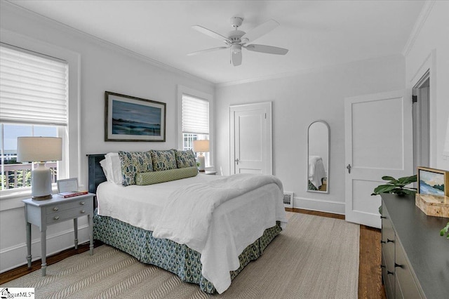bedroom featuring baseboards, crown molding, wood finished floors, and visible vents