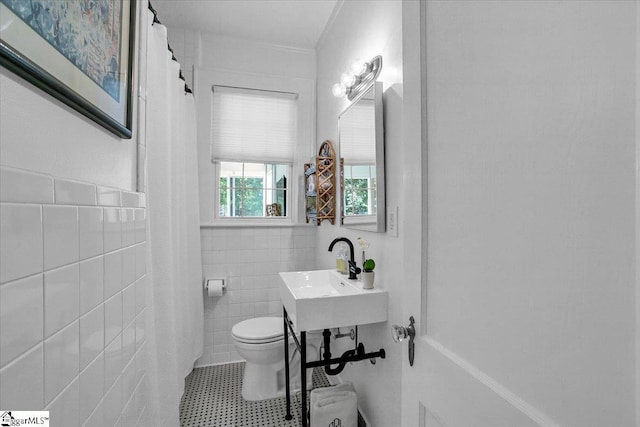 full bath with tile walls, toilet, wainscoting, and a sink