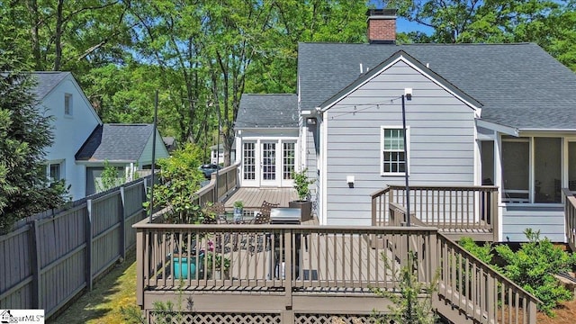 back of house featuring stairway, a chimney, fence, roof with shingles, and a deck