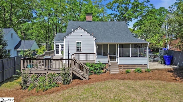 back of house featuring a sunroom, fence, a yard, and a shingled roof
