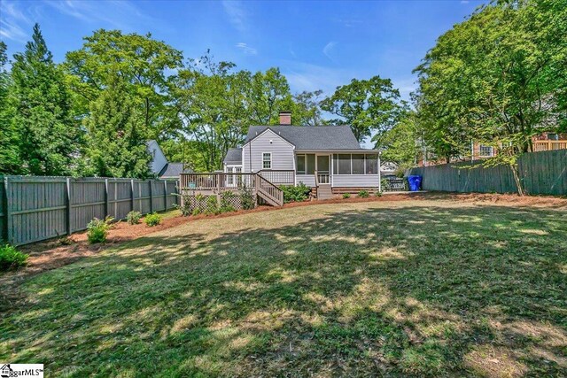 back of house with a fenced backyard, a wooden deck, stairs, a yard, and a sunroom
