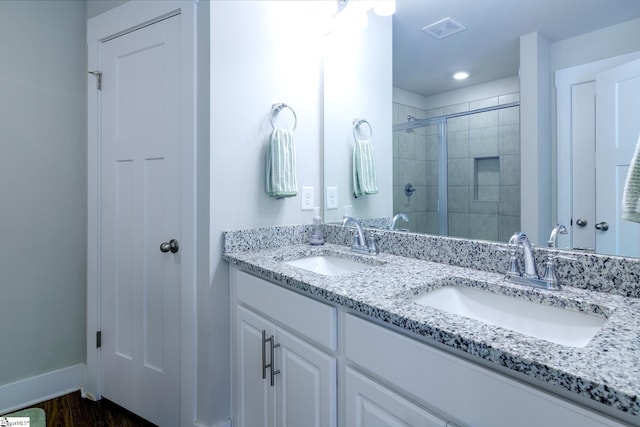 full bath featuring a tile shower, baseboards, a sink, and visible vents