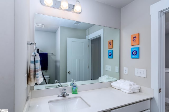 half bath with visible vents, toilet, baseboards, and vanity