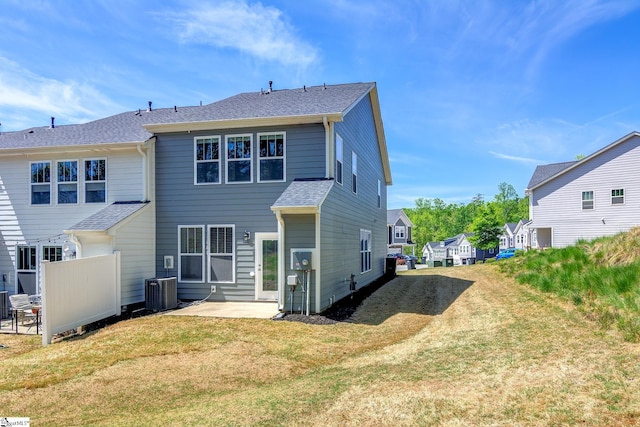 back of property featuring central air condition unit, fence, a shingled roof, a yard, and a patio