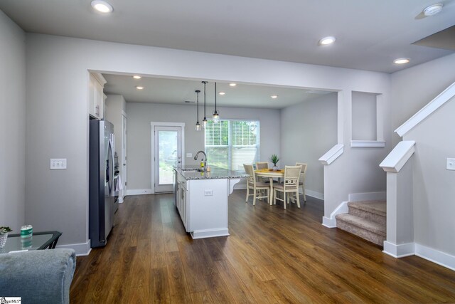 kitchen featuring a sink, dark wood-style flooring, white cabinetry, light stone countertops, and stainless steel refrigerator with ice dispenser