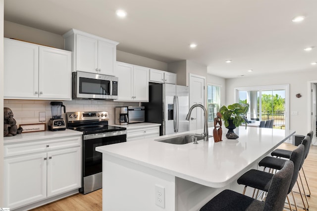 12 Hargrove Ct, Greenville, SC 29617 - kitchen with light wood finished floors, a kitchen island with sink, a sink, tasteful backsplash, and appliances with stainless steel finishes