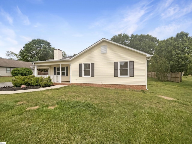view of front facade with a chimney, a front lawn, fence, and covered porch