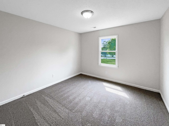unfurnished room featuring baseboards and dark colored carpet