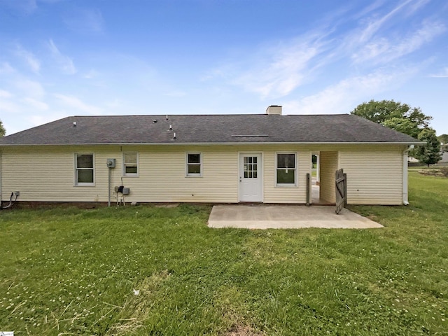 rear view of house with a yard, a chimney, and a patio