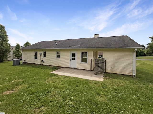rear view of property with a lawn, a chimney, central AC unit, and a patio
