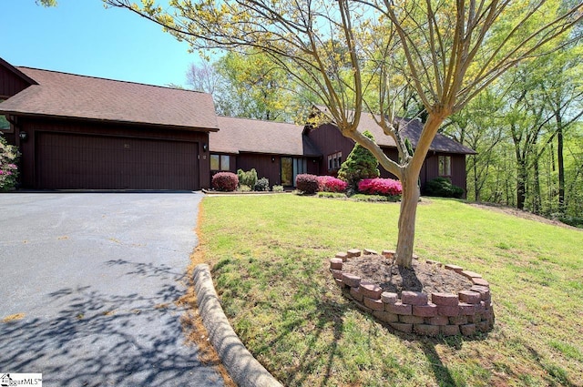 single story home with driveway, an attached garage, a shingled roof, board and batten siding, and a front yard