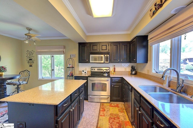 kitchen with a wealth of natural light, appliances with stainless steel finishes, a sink, and a kitchen island
