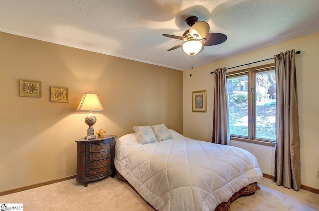 bedroom with ceiling fan, baseboards, a textured ceiling, and light colored carpet