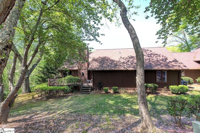 rear view of house featuring a shingled roof, a yard, and a deck