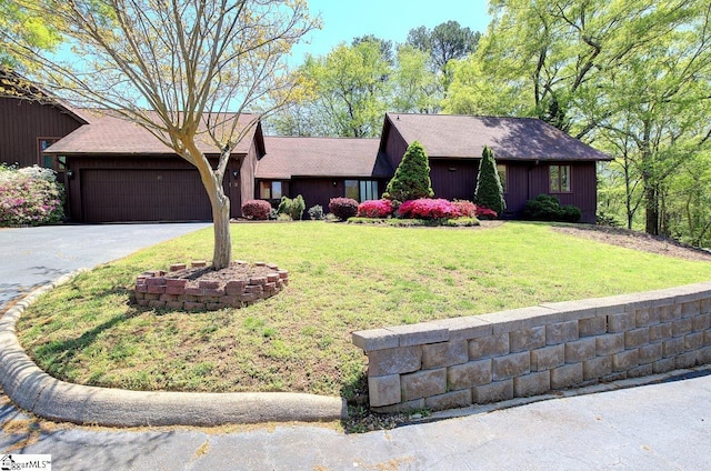 view of front facade featuring a front lawn, aphalt driveway, and a garage