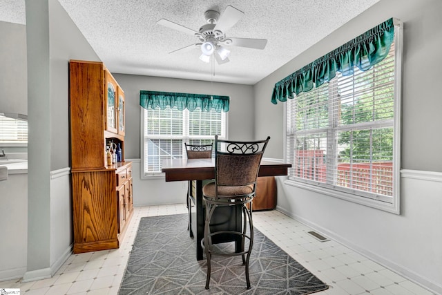 office area featuring a textured ceiling, baseboards, visible vents, ceiling fan, and light floors