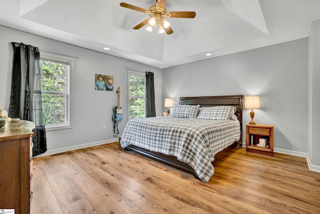 bedroom with wood finished floors, baseboards, and multiple windows