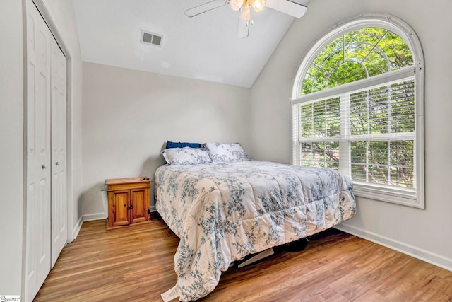 bedroom featuring vaulted ceiling, wood finished floors, a closet, baseboards, and visible vents