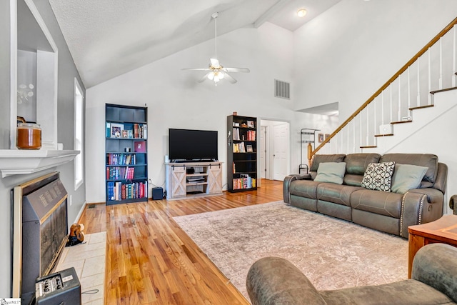 living area with stairway, high vaulted ceiling, wood finished floors, ceiling fan, and visible vents