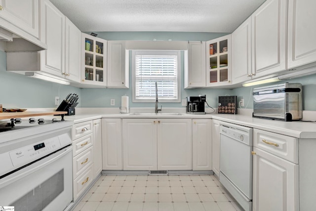 kitchen featuring light floors, white appliances, a sink, and white cabinets