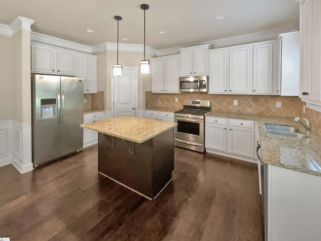 kitchen with a kitchen island, white cabinetry, appliances with stainless steel finishes, and crown molding