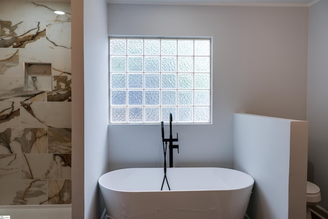 bathroom with a freestanding bath, a wealth of natural light, and toilet