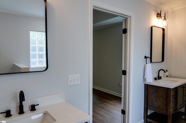 bathroom featuring baseboards, crown molding, vanity, and wood finished floors