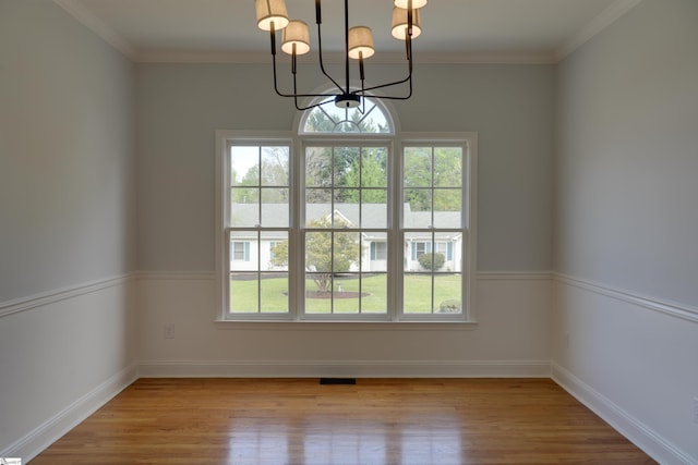 unfurnished dining area with wood finished floors, a wealth of natural light, and a notable chandelier