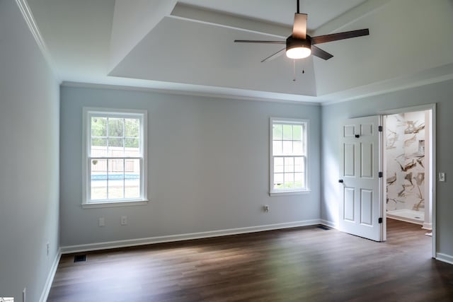 unfurnished bedroom with dark wood-style flooring, ornamental molding, multiple windows, and a raised ceiling