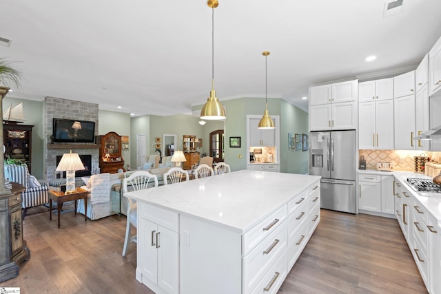 kitchen with tasteful backsplash, crown molding, a kitchen bar, appliances with stainless steel finishes, and a kitchen island