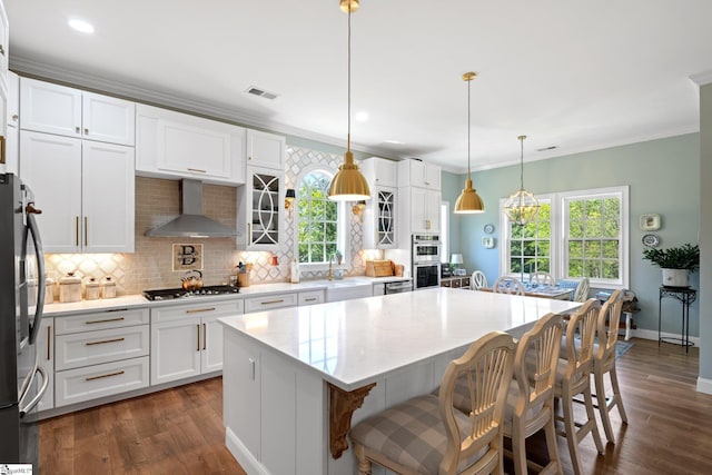 kitchen with wall chimney range hood, appliances with stainless steel finishes, tasteful backsplash, and dark wood-style floors