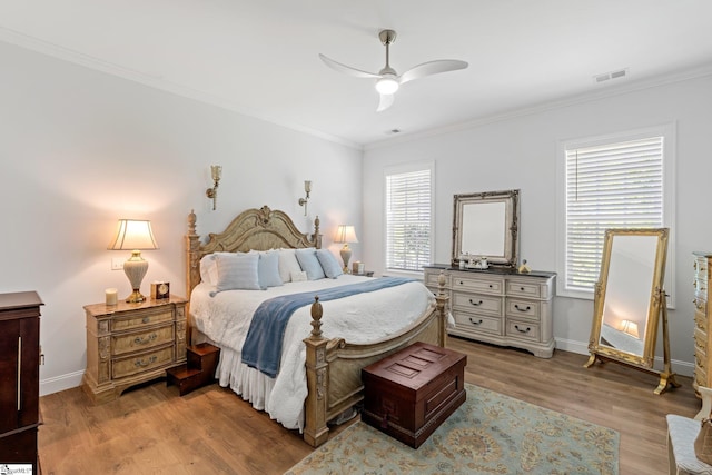 bedroom with a ceiling fan, crown molding, light wood-style floors, baseboards, and visible vents