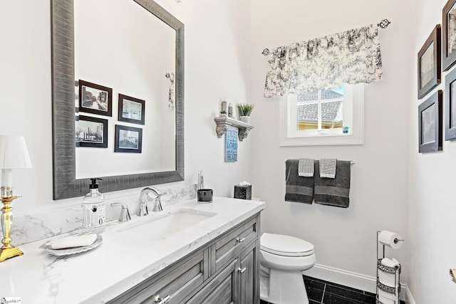bathroom with baseboards, vanity, and toilet