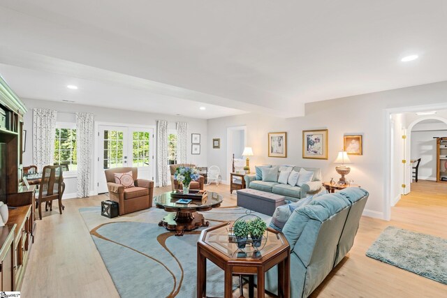 living room with recessed lighting, light wood-style floors, arched walkways, and baseboards