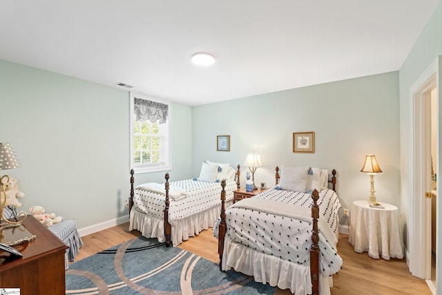 bedroom with baseboards, visible vents, and light wood finished floors