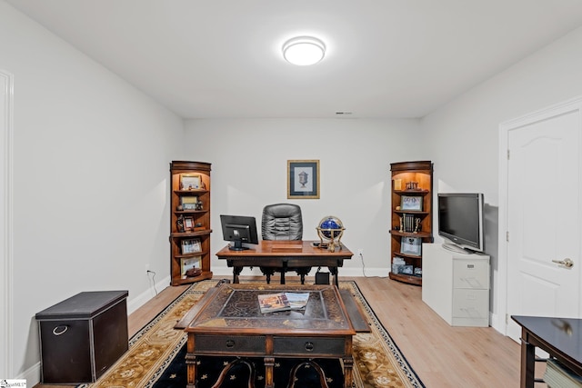 home office with visible vents, light wood finished floors, and baseboards