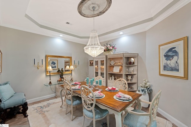 dining area featuring ornamental molding, baseboards, a notable chandelier, and a tray ceiling