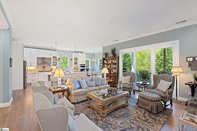 living room with visible vents, ornamental molding, and a healthy amount of sunlight