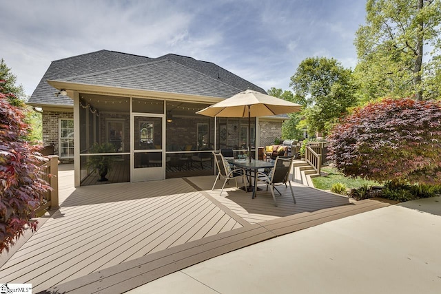 exterior space with a sunroom, outdoor dining area, and a deck