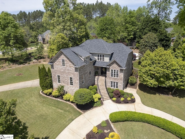 view of front facade featuring stone siding, a front yard, and stairway