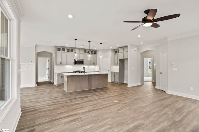 kitchen with stainless steel microwave, arched walkways, a ceiling fan, and recessed lighting