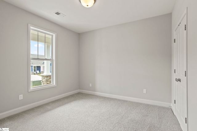 carpeted empty room featuring baseboards and visible vents