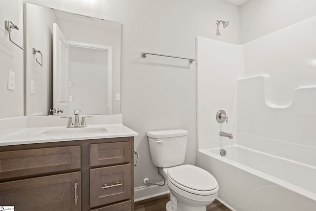 bathroom featuring wood finished floors, toilet, vanity, baseboards, and shower / tub combination