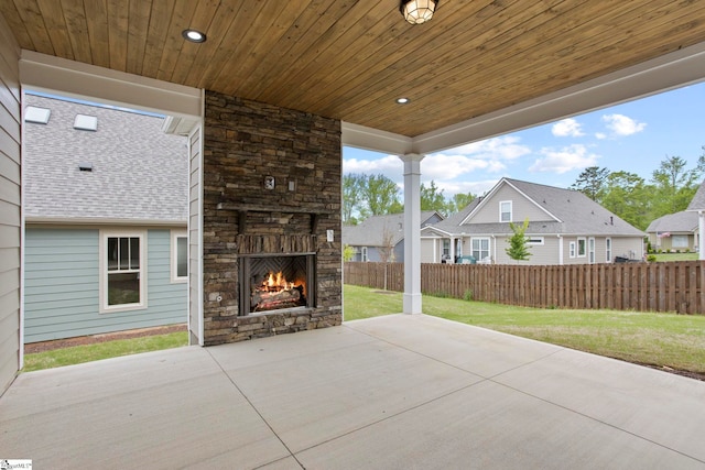 view of patio with fence, an outdoor stone fireplace, and a residential view