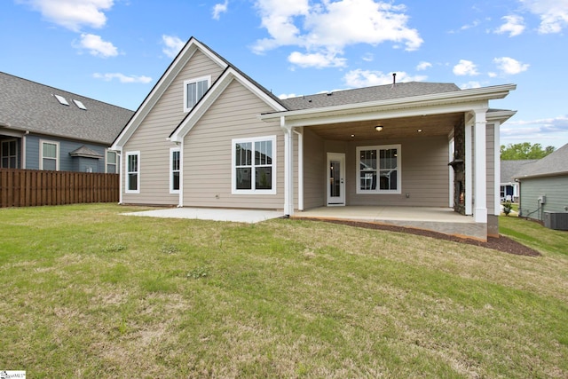 rear view of property with a lawn, fence, a patio area, and central AC