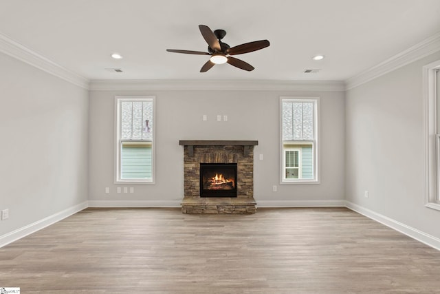 unfurnished living room with baseboards, wood finished floors, ceiling fan, a stone fireplace, and ornamental molding